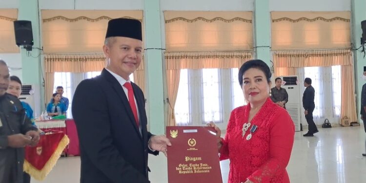 Bupati Gunung Mas, Jaya S Monong (kiri) menyerahkan penghargaan Satyalancana Karya Satya dari Presiden RI kepada salah satu PNS di lingkup pemkab setempat, di Kuala Kurun, Jumat, (28/10/2022). (IST)