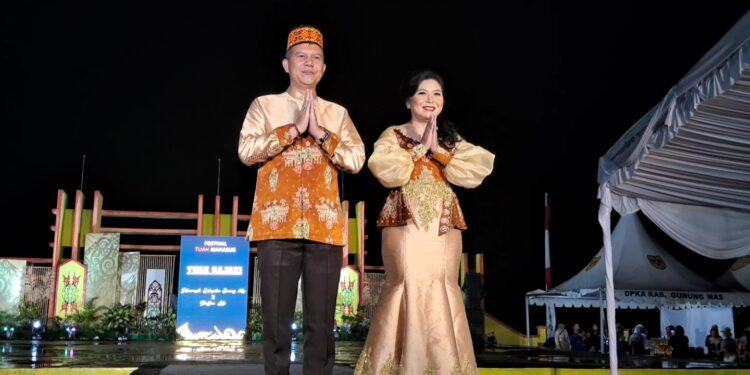 Bupati Gunung Mas, Jaya S Monong dan Ketua Dekranasda Gunung Mas, Mimie Mariatie Jaya S Monong mengenakan benang bintik khas Gunung Mas saat peluncuran benang bintik, pada malam puncak Festival Tuah Mahasur di Taman Kota Kuala Kurun, Jumat (28/10/2022). (MASAPNEWS/GCM)