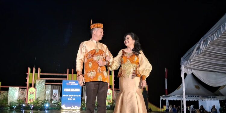 Bupati Gunung Mas, Jaya S Monong dan Ketua Dekranasda Mimie Mariatie Jaya S Monong ikut meluncurkan salah satu busana benang bintik khas kabupaten, saat malam puncak Festival Tuah Mahasur di Taman Kota Kuala Kurun, Jumat (28/10/2022). (MASAPNEWS/GCM)