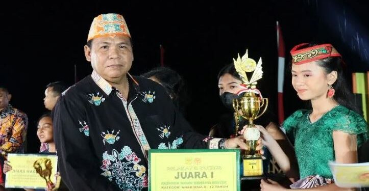 Legislator Kabupaten Gunung Mas, Punding S Merang (kiri) menyerahkan piala kepada salah satu pemenang lomba fashion show benang bintik, pada malam puncak Festival Tuah Mahasur di Taman Kota Kuala Kurun, Jumat (28/10/2022). (Foto : Diskominfosantik Gunung Mas)