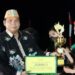 Legislator Kabupaten Gunung Mas, Punding S Merang (kiri) menyerahkan piala kepada salah satu pemenang lomba fashion show benang bintik, pada malam puncak Festival Tuah Mahasur di Taman Kota Kuala Kurun, Jumat (28/10/2022). (Foto : Diskominfosantik Gunung Mas)