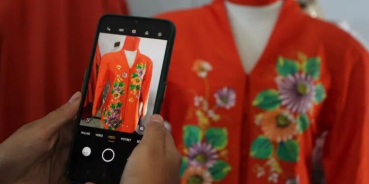 Anggota komunitas Forum Industri Kecil Menengah (IKM) memotret produk busana lukis miliknya untuk diunggah di laman pasar digital di Galeri IKM Malang, Jawa Timur, Jumat (29/7/2022). Sebanyak 90 perajin dan pelaku Usaha Kecil Menengah (UKM) setempat menggabungkan diri ke komunitas tersebut sebagai upaya memperkuat jaringan pemasaran serta memperluas jangkauan pasar. (MASAPNEWS/ANT)