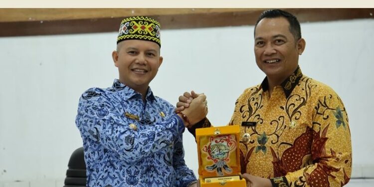 Bupati Gunung Mas, Jaya S Monong (kiri) bertukar cendera mata dengan Bupati Bengkayang, Sebastianus Darwis, di Kuala Kurun, Jumat (17/3/2023). (Foto : Diskominfosantik Gunung Mas)