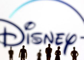 Sosok mainan orang terlihat di depan logo Disney + yang ditampilkan dalam ilustrasi. (MASAPNEWS/ANT/REUTERS)
