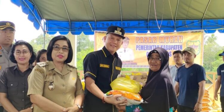 Bupati Gunung Mas, Jaya S Monong didampingi Wakil Bupati Efrensia LP Umbing menyerahkan paket bahan pokok kepada salah satu warga, saat pelaksanaan pasar murah di Kuala Kurun, Senin (3/4/2023). (Foto : Protokol dan Perjalanan Setda Gunung Mas)