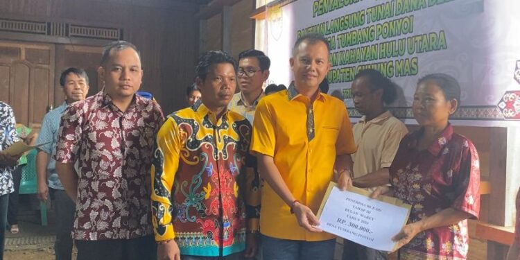 Bupati Gunung Mas Jaya S Monong, didampingi Kepala Desa Tumbang Ponyoi Melky Sudiarjo dan Anggota DPRD Gunung Mas Evandi, menyalurkan BLT DD secara simbolis kepada sejumlah KPM di desa setempat, Minggu (21/5/2023). (Foto : Protokol dan Perjalanan Setda Gunung Mas)