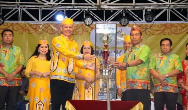 Bupati Gumas Jaya S Monong menyerahkan piala bergilir FBMM kepada Kepala Disbudpar Kabupaten Gumas Hansli Gonak, saat pembukaan FBMM di Stadion Mini Kuala Kurun, Sabtu (17/6/2023). (Foto : Diskominfosantik Kabupaten Gumas)