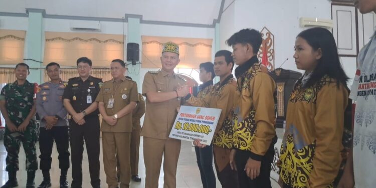 Bupati Gunung Mas Jaya S Monong menyerahkan uang saku kepada salah satu atlet peraih medali. (MASAPNEWS/GCM)