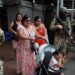 Sejumlah warga berjalan melewati tentara bersenjata, saat mereka menjaga kawasan komersial, menyusul gelombang kekerasan yang menyebabkan penyerbuan stasiun TV dan ledakan di seluruh wilayah, di Quito, Ekuador (11/4/2024). (MASAPNEWS/ANT/REUTERS)