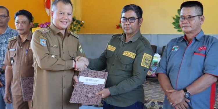 Bupati Gunung Mas Jaya S Monong menyerahkan secara simbolis SK peserta kebun plasma kepada Camat Damang Batu Sudirman, di Desa Tumbang Maraya Kecamatan Damang Batu, Selasa (27/2/2024). (Foto : Diskominfosantik Gunung Mas)