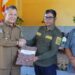 Bupati Gunung Mas Jaya S Monong menyerahkan secara simbolis SK peserta kebun plasma kepada Camat Damang Batu Sudirman, di Desa Tumbang Maraya Kecamatan Damang Batu, Selasa (27/2/2024). (Foto : Diskominfosantik Gunung Mas)