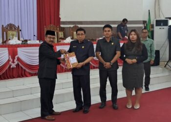 Pj Bupati Gumas Herson B Aden sampaikan Raperda Pertanggungjawaban Pelaksanaan APBD 2023 kepada Ketua DPRD Akerman Sahidar, saat rapat paripurna di Kuala Kurun, Rabu (19/6/2024). (MASAPNEWS/GCM)