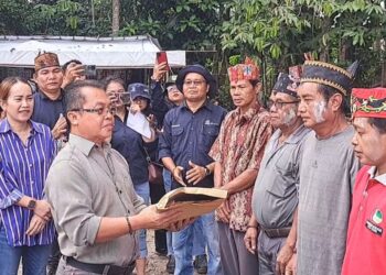 Legislator Kabupaten Gunung Mas Nomi Aprilia (baju garis-garis) mendampingi Asisten III Setda Gumas Letus Guntur saat penyerahan bantuan program pokir untuk pelaksanaan Tiwah massal di Kelurahan Tampang Tumbang Anjir Kecamatan Kurun, Sabtu (8/5/2024). (MASAPNEWS/GCM)