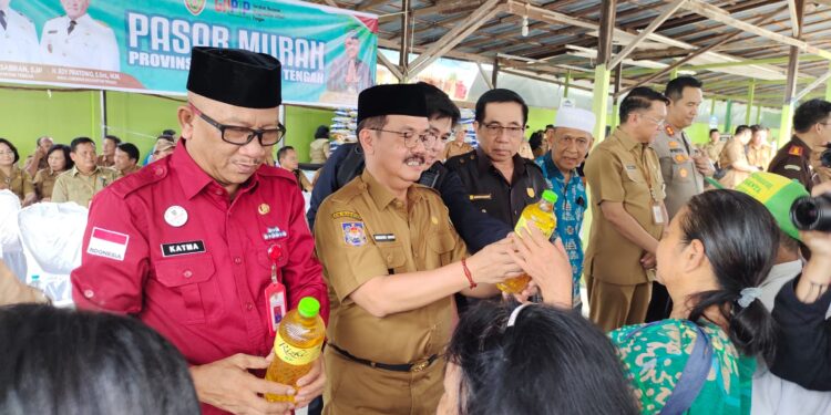 Penjabat Bupati Gumas Herson B Aden menunjukkan paket bahan pokok pada pembukaan pasar murah di Kuala Kurun, Selasa (11/6/2024). (IST)