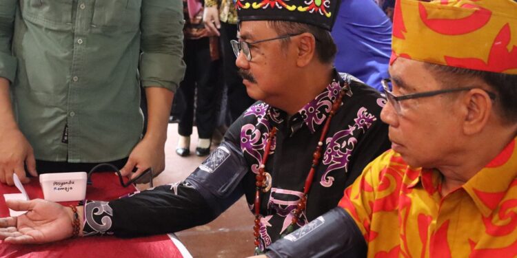 Ketua DPRD Kabupaten Gumas Akerman Sahidar (batik oranye) dan Pj Bupati Herson B Aden, mencoba pelayanan publik pemeriksaan kesehatan di stan pameran pembangunan, di Kuala Kurun, Minggu (16/6/2024). (Foto : Diskominfosantik Gumas)