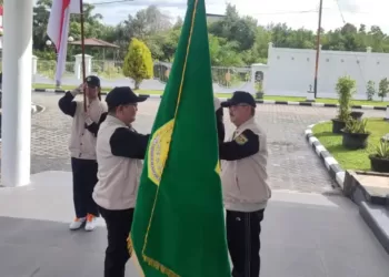 Penjabat Bupati Gumas Herson B Aden (kanan) menyerahkan duaja kabupaten kepada Kepala Disdikpora Aprianto saat pelepasan kontingen di Kuala Kurun, Senin (1/7/2024). (Foto : Diskominfosantik Gumas)