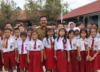 Pj Bupati Gumas Herson B Aden, Kepala SDN 3 Kuala Kurun Belie, berfoto bersama peserta didik di SD setempat, Senin (15/7/2024). (Foto : Diskominfosantik Gumas)