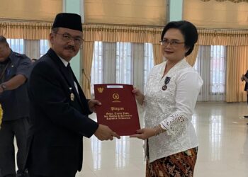 Penjabat Bupati Gumas Herson B Aden menyerahkan piagam penghargaan Satyalancana Karya Satya kepada salah satu PNS di Kuala Kurun, Kamis (15/8/2024). (IST)