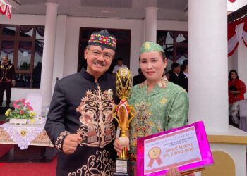 Pj Bupati Gumas Herson B Aden berfoto bersama Kepala Puskesmas Rabambang Sri Lastari usai penyerahan piala dan piagam penghargaan di Kuala Kurun, Sabtu (17/8/2024). (IST)