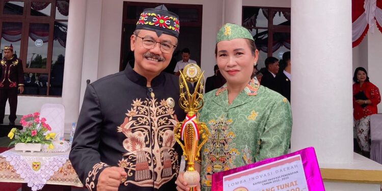 Pj Bupati Gumas Herson B Aden berfoto bersama Kepala Puskesmas Rabambang Sri Lastari usai penyerahan piala dan piagam penghargaan di Kuala Kurun, Sabtu (17/8/2024). (IST)