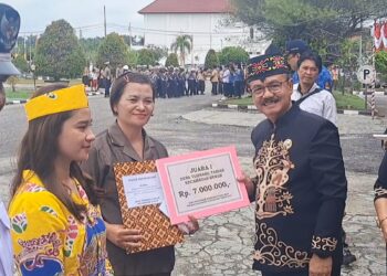 Pj Bupati Gumas Herson B Aden menyerahkan piagam dan uang pembinaan kepada Tumbang Tariak, yang diwakili Ketua BPD Diana di Kuala Kurun, Sabtu (17/8/2024). (IST)