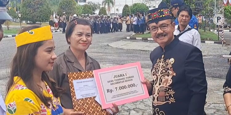 Pj Bupati Gumas Herson B Aden menyerahkan piagam dan uang pembinaan kepada Tumbang Tariak, yang diwakili Ketua BPD Diana di Kuala Kurun, Sabtu (17/8/2024). (IST)