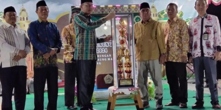 Sekda Gumas Richard (batik hijau) menyerahkan piala kepada Camat Rungan Penyang Massal saat penutupan MTQ ke-17 tingkat kabupaten di Kecamatan Rungan, Sabtu malam (26/10/2024). (ist)