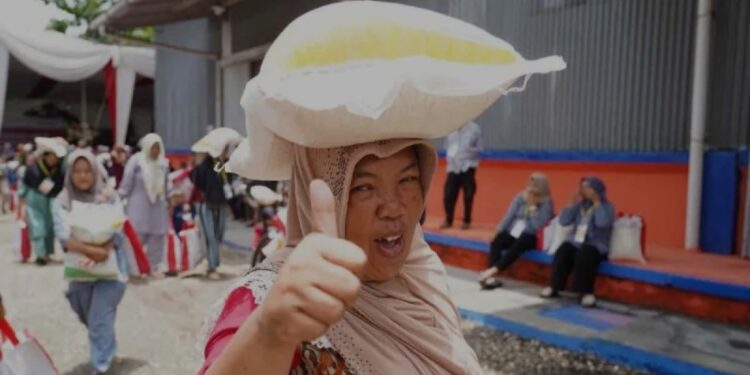 Ilustrasi - Seorang ibu menjunjung bantuan pangan beras 10 kilogram (kg) sambil mengacungkan jempol. (MASAPNEWS/ANT/HO-Humas Bapanas)