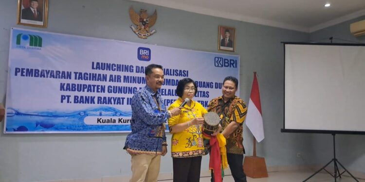 Wakil Bupati Gumas Efrensia LP Umbing (tengah), didampingi Direktur Perumdam Maruang Duhung Hendra Toendan (kiri) dan Pimpinan KCP BRI Kuala Kurun Utas Wenly, memukul katambung tanda diluncurkannya pembayaran tagihan air perumdam melalui layanan BRI, di Kuala Kurun, Selasa sore (18/3/2025). (Foto : MASAPNEWS)