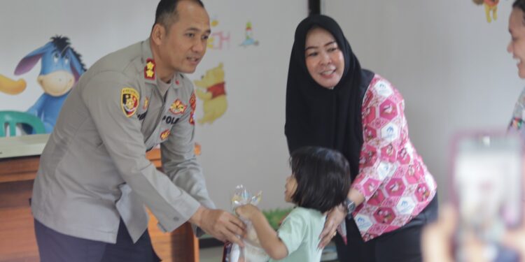 Kapolres Gunung Mas, AKBP Heru Eko Wibowo, S.I.K., M.H. memberi bingkisan makanan bergizi atau MPASI kepada salah satu anak saat berkunjung ke Puskesmas Kemala di Kuala Kurun, Kamis (8/5/2025). (IST)