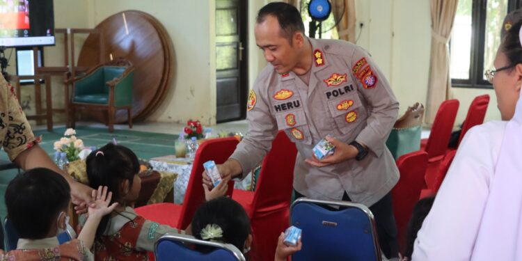 Kapolres Gunung Mas membagikan susu kepada anak-anak saat pelaksanaan Gebyar Posyandu Presisi di Aula Patria Tama, Jalan Bhayangkara No 1 Kelurahan Tampang Tumbang Anjir, Kecamatan Kurun, Kamis (22/5/2025). (IST)