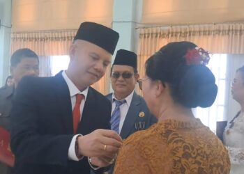 Bupati Gumas Jaya S Monong, didampingi Plt Kepala BKPSDM Guanhin (berkacamata) menyematkan penghargaan Satyalancana Karya Satya kepada salah satu PNS, di Kuala Kurun, Minggu (17/8/2025). (MASAPNEWS/GCM)