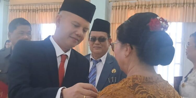 Bupati Gumas Jaya S Monong, didampingi Plt Kepala BKPSDM Guanhin (berkacamata) menyematkan penghargaan Satyalancana Karya Satya kepada salah satu PNS, di Kuala Kurun, Minggu (17/8/2025). (MASAPNEWS/GCM)