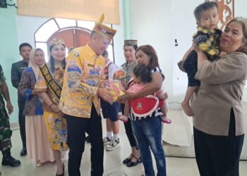 Bupati Gumas Jaya S Monong didampingi Ketua TP PKK kabupaten Mimie Mariatie menyalurkan bantuan nutrisi program Genting kepada salah satu penerima manfaat, saat peringatan HAN dan Harganas tingkat kabupaten di Kuala Kurun, Kamis (4/9/2025). (MASAPNEWS/GCM)