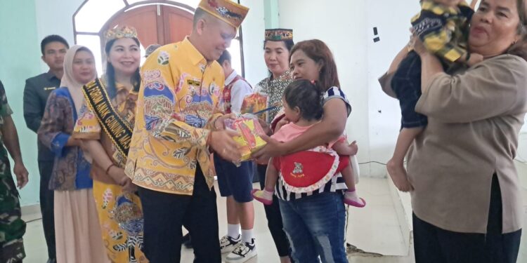Bupati Gumas Jaya S Monong didampingi Ketua TP PKK kabupaten Mimie Mariatie menyalurkan bantuan nutrisi program Genting kepada salah satu penerima manfaat, saat peringatan HAN dan Harganas tingkat kabupaten di Kuala Kurun, Kamis (4/9/2025). (MASAPNEWS/GCM)