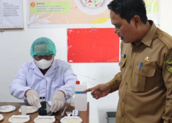Kepala DPKP Gumas Eigh Manto melihat proses uji chlorine yang dilakukan pegawai dinas tersebut terhadap sejumlah sampel beras di Kuala Kurun, Selasa (29/7/2025). (IST)
