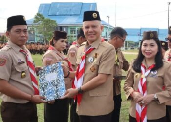 Bupati Gumas Jaya S Monong didampingi Ketua Kwarcab Mimie Mariatie menyerahkan piagam Lencana Pancawarsa kepada salah satu anggota Pramuka di Kuala Kurun, Jumat (7/11/2025). (IST)
