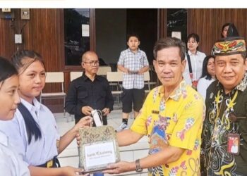 Sekretaris Dinsos Gumas Donie (batik kuning), didampingi Pimpinan Bank Kalteng Cabang Kuala Kurun Empas S Umar, menyalurkan CSR dari Bank Kalteng kepada salah satu peserta didik Sekolah Rakyat di Kuala Kurun, Kamis, 6 November 2025. (IST)